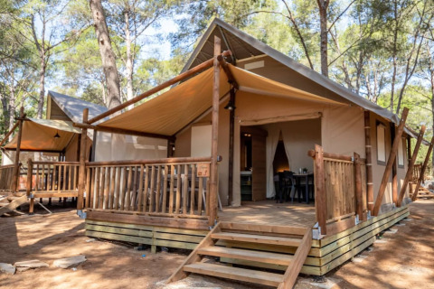 Safari tent Torre del Sol TIENDA SAVANNAH featuring a wooden deck, canopy, and tree-filled natural setting.