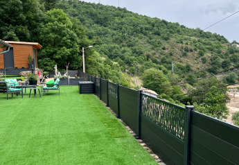 Vista dal Chalet Cheylard in Francia con prato artificiale, salotto da esterno e colline boscose verdi.