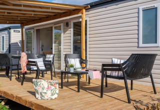 Houten terras met zwarte tuinstoelen bij een stacaravan op Camping Estival Vendrell Plajta, Spanje.