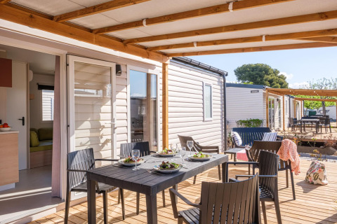 Overdekt terras met eettafel en vier stoelen bij stacaravan, Camping Estival Vendrell Platja, Spanje.