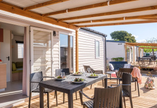 Überdachte Terrasse mit Esstisch und vier Stühlen vor Mobilheim, Camping Estival Vendrell Platja in Spanien.