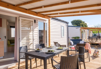 Überdachte Terrasse mit Esstisch und vier Stühlen vor Mobilheim, Camping Estival Vendrell Platja in Spanien.