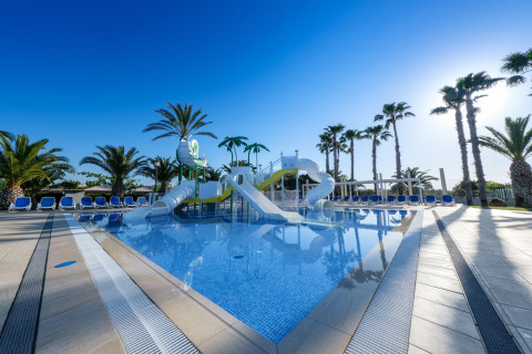 Außenpool mit Wasserrutschen und Palmen im CAMPING ESTIVAL VENDRELL PLATJA, Mobilheim Mediterranean für 4 Personen, Spanien.