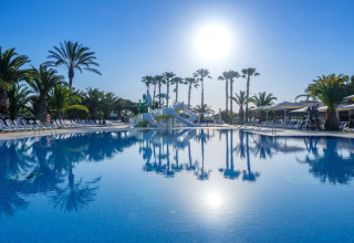 Buitenzwembad bij Camping Estival Vendrell Platja stacaravan in Spanje met palmbomen en zon