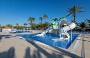 Piscine extérieure avec toboggans et palmiers au Camping Estival Vendrell Platja Tent Grand Safari Glamping en Espagne.