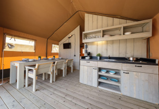 Vue intérieure d’une tente safari glamping avec cuisine rustique et coin repas en Espagne.
