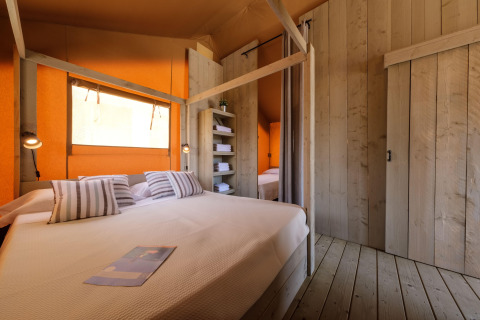 Indretning af soveværelse i CAMPING ESTIVAL VENDRELL PLATJA TENT GRAND SAFARI GLAMPING med trævægge og dobbeltseng.