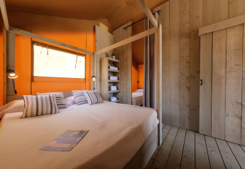 Schlafzimmer im CAMPING ESTIVAL VENDRELL PLATJA TENT GRAND SAFARI GLAMPING mit Holzdekor, Doppelbett und gemütlicher Atmosphäre.