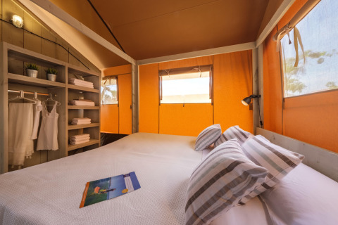 Indretning af et komfortabelt soveværelse i en safari glamping-telt på Estival Vendrell Platja i Spanien.