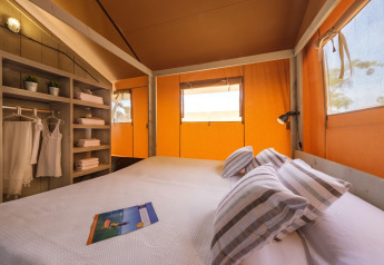 Chambre confortable dans une tente safari glamping à Estival Vendrell Platja, en Espagne, avec lumière.