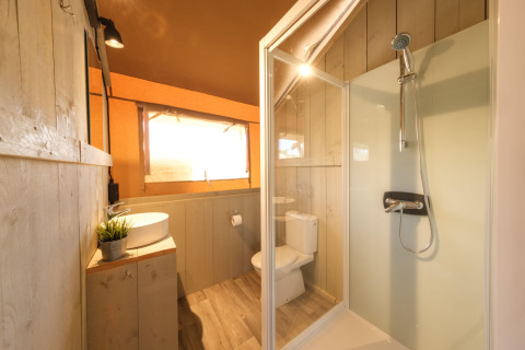 Badeværelse i en luksuriøs safari-telt med brusekabine, håndvask og toilet på Camping Estival Vendrell.