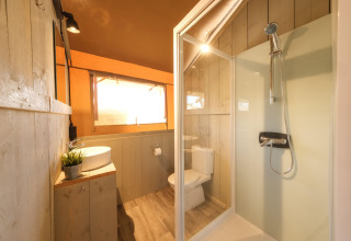 Badeværelse i en luksuriøs safari-telt med brusekabine, håndvask og toilet på Camping Estival Vendrell.
