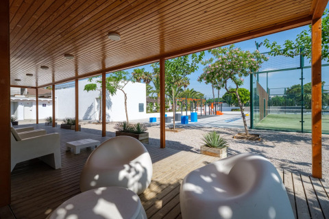 Udendørs opholdsområde på Camping Estival Vendrell Platja Tent Grand Safari Glamping i Spanien med moderne stole, fælles faciliteter og sportsbaner under åben himmel.