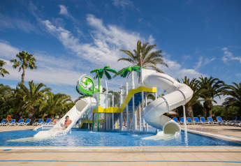 Wasserpark mit Rutschen und Palmen im Camping Estival Vendrell Platja Tent Grand Safari Glamping in Spanien.