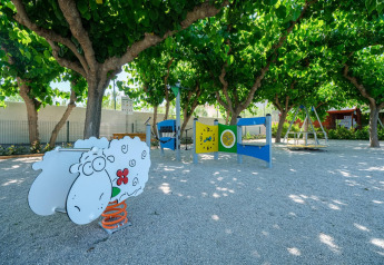 Parque infantil con figura de oveja, columpios y árboles en Camping Estival Vendrell Platja Tent Grand Safari, España.
