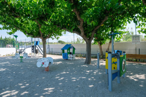 Aire de jeux ombragée avec balançoires, toboggan et cabane au Camping Estival Vendrell Platja, Espagne.