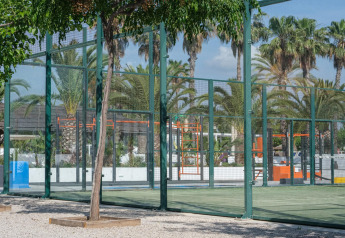 Terrain de padel avec murs en verre et palmiers à l’arrière au Camping Estival Vendrell Platja, Espagne.