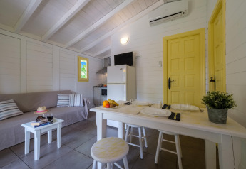 Interieur van bungalow met bank, eettafel, keuken en gele deuren bij Vendrell Platja Camping in Spanje.