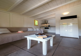 Intérieur d’un bungalow lumineux avec canapé, table basse, cuisine et réfrigérateur à Vendrell Platja, Espagne.