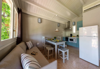Cuisine et coin repas lumineux dans un bungalow au Camping Estival Vendrell Platja, Espagne, avec canapé et table.