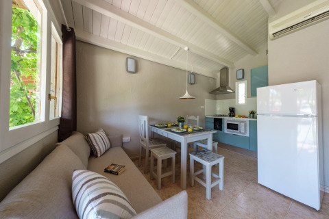 Lyst køkken og spisestue i et bungalow på Camping Estival Vendrell Platja, Spanien, med sofa og spisebord.