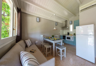Lyst køkken og spisestue i et bungalow på Camping Estival Vendrell Platja, Spanien, med sofa og spisebord.