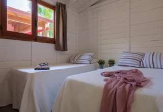Lyst bungalowværelse med to enkeltsenge, planter og vindue hos CAMPING ESTIVAL VENDRELL PLATJA i Spanien.