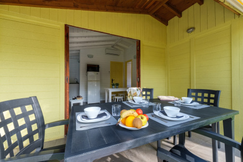 Udendørs spiseområde på Camping Estival Vendrell Platja Bungalow 4 Standard med dækket bord og frugtskål.