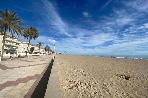 Strandbillede ved Camping Estival Vendrell Platja Bungalow 4 Standard med palmer og promenade i Spanien.