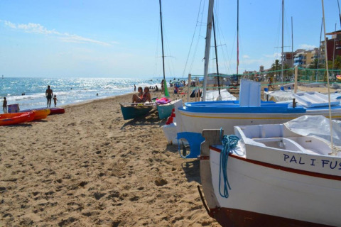 Sandstrand med både og mennesker ved Camping Estival Vendrell Platja Bungalow 4 Standard i Spanien.