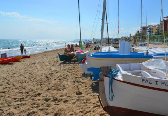 Zandstrand met boten en mensen bij Camping Estival Vendrell Platja Bungalow 4 Standard in Spanje.