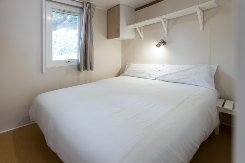 Soveværelse i mobilhome Camping Cambrils Playa BUNGALOW OHARA i Spanien med dobbeltseng og vindue.
