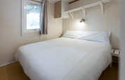 Slaapkamer in mobilhome Camping Cambrils Playa BUNGALOW OHARA in Spanje met tweepersoonsbed en raam.