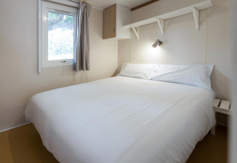 Slaapkamer in mobilhome Camping Cambrils Playa BUNGALOW OHARA in Spanje met tweepersoonsbed en raam.