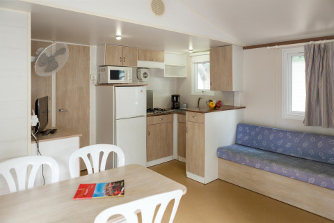 Mobilhome-interiør fra Camping Cambrils Playa BUNGALOW OHARA i Spanien, med køkken og sofaområde.