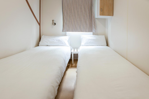 Et lyst og enkelt soveværelse med to enkeltsenge i mobilhjemmet Camping Cambrils Playa BUNGALOW OHARA i Spanien.