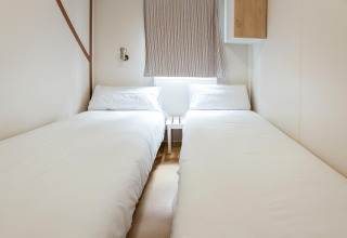 Et lyst og enkelt soveværelse med to enkeltsenge i mobilhjemmet Camping Cambrils Playa BUNGALOW OHARA i Spanien.