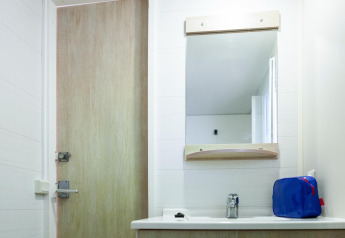 Badkamer in een stacaravan op Camping Cambrils Playa met spiegel, wastafel en blauwe toilettas.