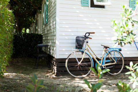 Cykel parkeret foran et mobilhome med hvide vægge og grønne skodder ved Camping Cambrils Playa BUNGALOW OHARA i Spanien.