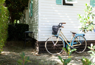 Cykel parkeret foran et mobilhome med hvide vægge og grønne skodder ved Camping Cambrils Playa BUNGALOW OHARA i Spanien.
