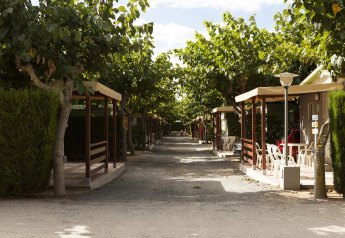Mobilhome laan bij Camping Cambrils Playa BUNGALOW OHARA in Spanje, met bomen en veranda's.