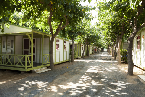 Mobilhjem ved Camping Cambrils Playa BUNGALOW OHARA i Spanien, omgivet af træer og grussti.