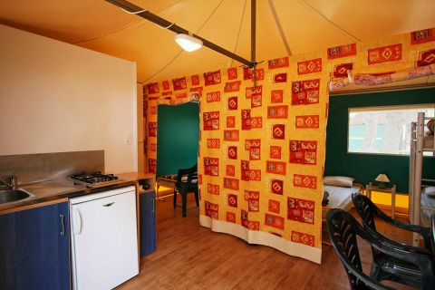 Interiør af mobilhome Torre del Sol Tent Pagan i Spanien med køkken, gardin og senge.