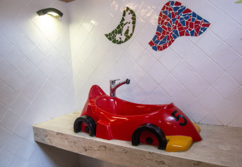 Lavabo a forma di auto da corsa rossa su piano in pietra, mosaici colorati, foto in alloggio glamping.