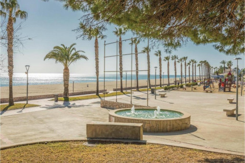 Udsigt over strandpromenaden ved Torre del Sol Tent Pagan i Spanien med palmer, springvand og legeplads.