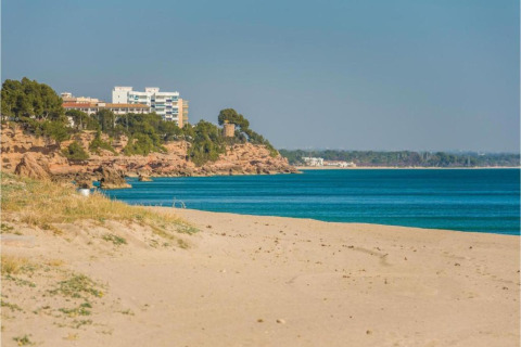 Strandudsigt fra mobilhjemmet Torre del Sol Tent Pagan i Spanien med blå himmel og klipper.