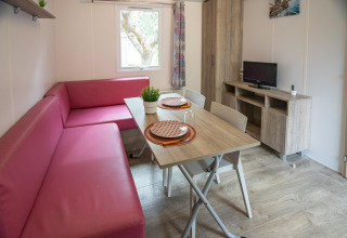 Sala de estar en Torre del Sol COTTAGE PALMA en España con sofá rosa, mesa de comedor y televisor.