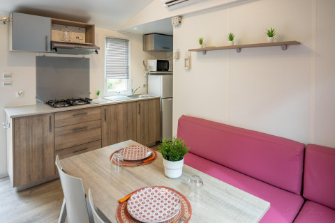 Cocina moderna y comedor en Torre del Sol COTTAGE PALMA, España, con sofá rosa y mesa de madera.