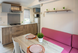 Cocina moderna y comedor en Torre del Sol COTTAGE PALMA, España, con sofá rosa y mesa de madera.