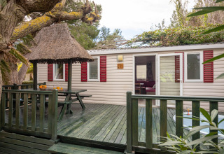 Mobilhjemmet Torre del Sol Cottage i Spanien med grøn veranda, stråtag og røde skodder.